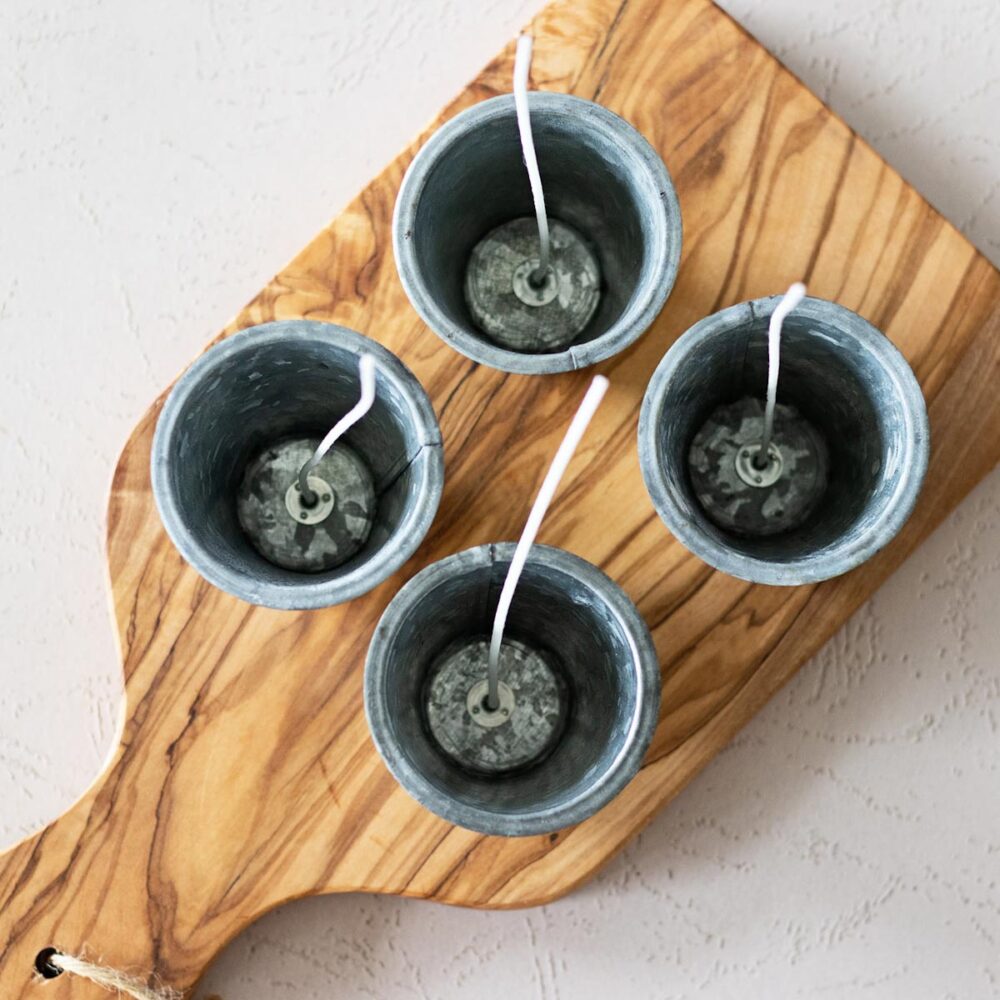 Rustic sugar mold candle cups prepped with wicks ready for wax on an olive wood board.